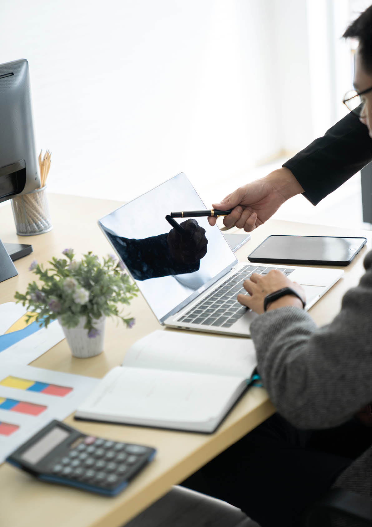 Helpful male boss mentor coach teacher explaining new online project to young male worker intern student, focused leader executive manager teaching student instruct trainee pointing at pc computer