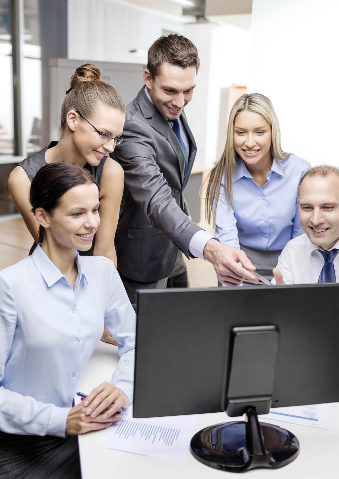 business, technology and office concept - smiling business team with computer monitor having discussion in office