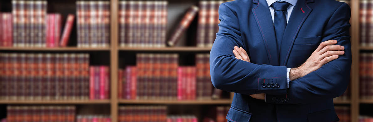 Portrait Of Confident Attorney Standing Arms Crossed Against Bookshelf In Office