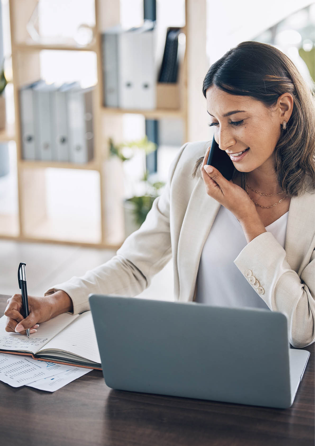 Lawyer, laptop and phone call for notebook writing, policy review feedback or legal consulting schedule in corporate law firm. Smile, happy and talking attorney woman on mobile technology or laptop.