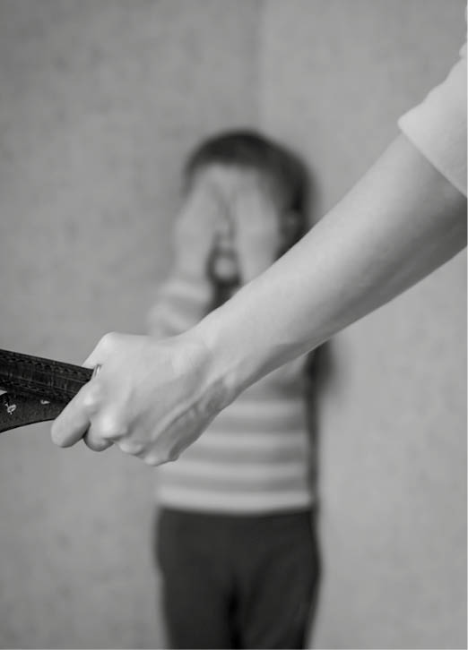 Mom with a belt stands in front of the child  The son is crying in the corner  Domestic violence against children 
