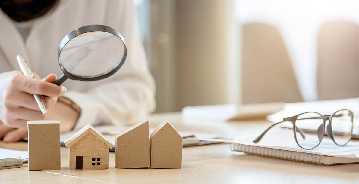 Looking for real estate agency, property insurance, mortgage loan or new house  Woman with magnifying glass over a wooden house at her office 