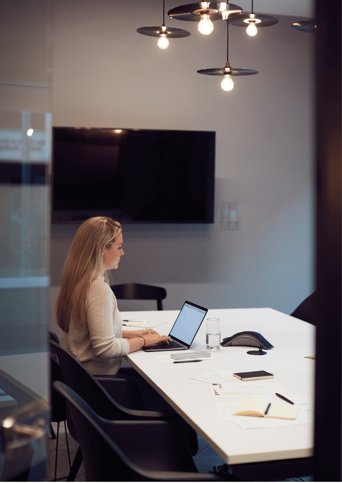 Businesswoman Working Late In Office Meeting Room Using Laptop