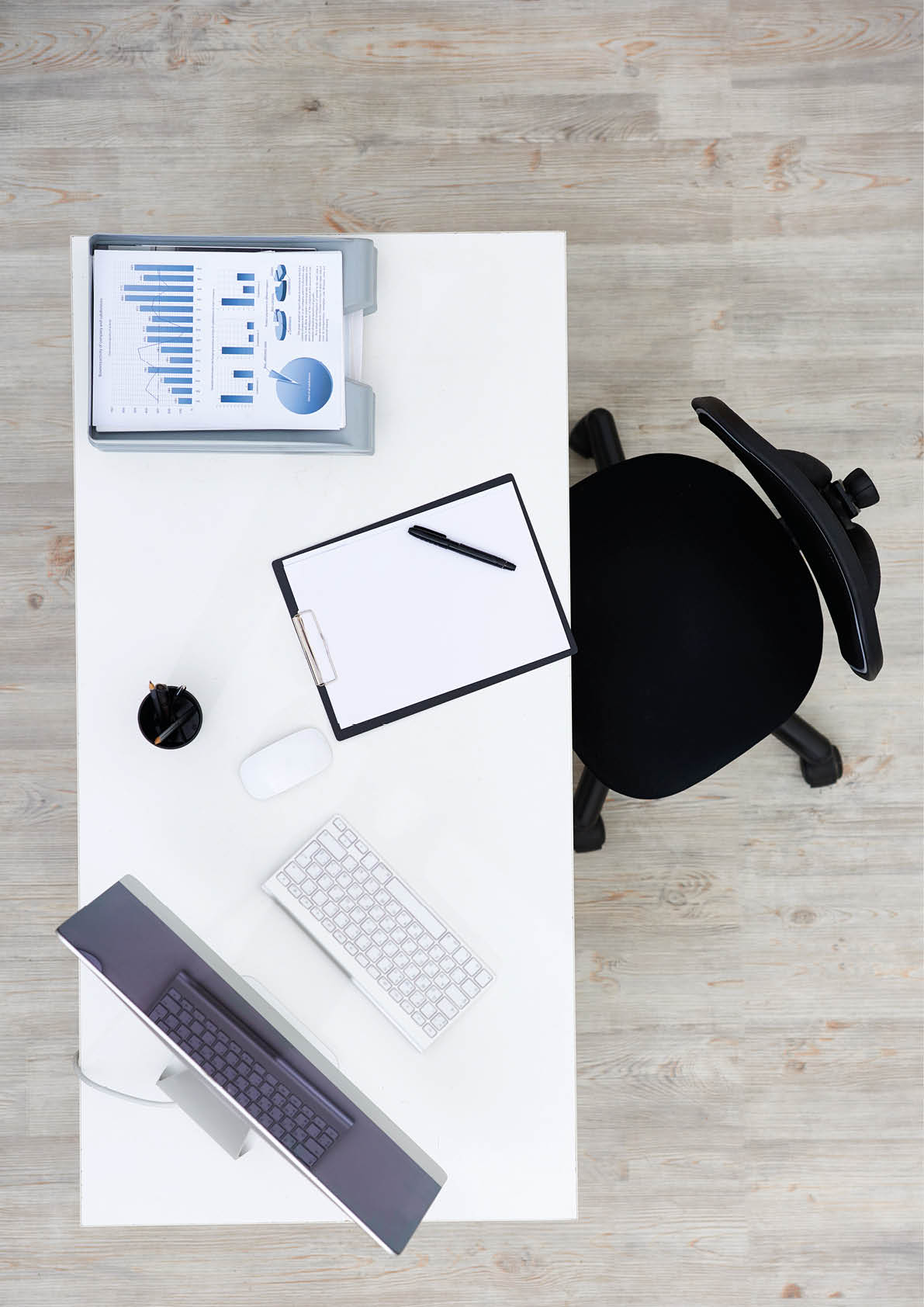 Directly above view of modern workplace: swivel chair and wooden desk with computer, documents and other stationery, no people