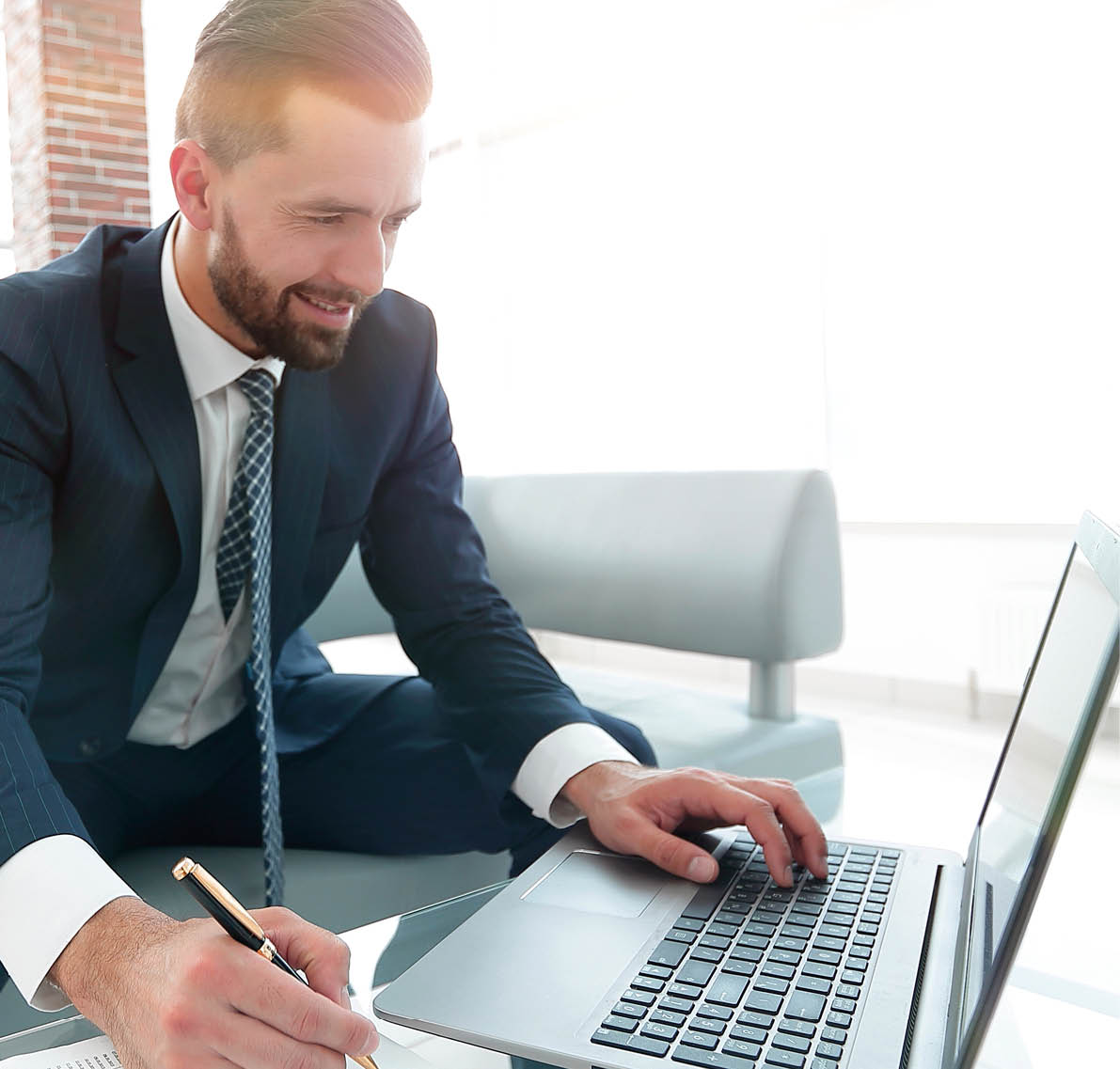 Stylish man working on laptop and making notes in notebook  Photo with copy space