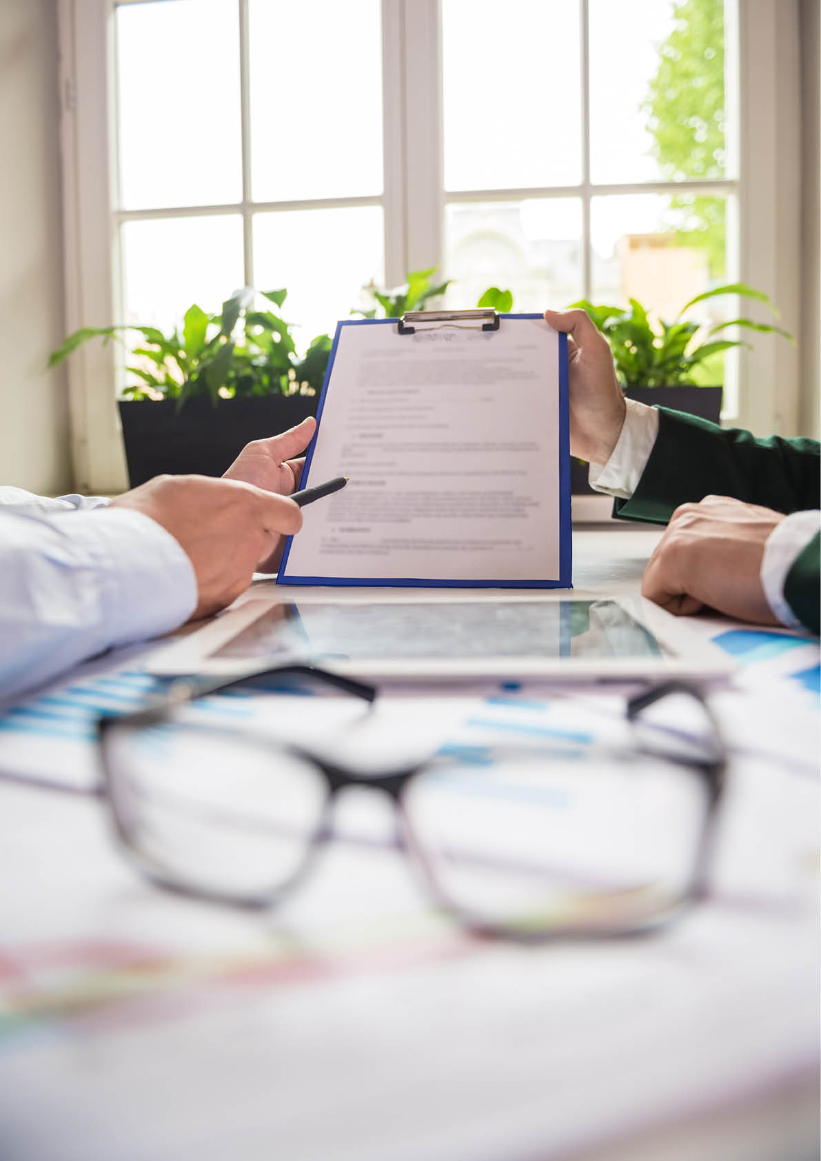Close-up of male hands holding tablet and discussing the contract at office 