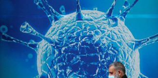 Los casos del virus en todo el mundo superan los 22,42 millones y las muertes alcanzan las 785.306 FOTO DE ARCHIVO: Un hombre con una mascarilla camina frente a una ilustración de un virus en el exterior de un centro científico regional en Oldham, Reino Unido, el 3 de agosto de 2020. REUTERS/Phil Noble