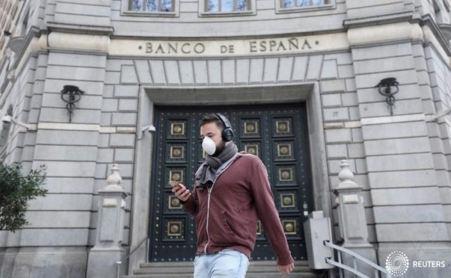 A man wears a protective face mask as he walks past Banco de Espana (Bank of Spain), amidst concerns over coronavirus outbreak, in Barcelona, Spain March 14, 2020. REUTERS/Nacho Doce/File Photo