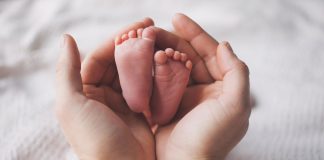 Conceden el complemento de maternidad a un varón que sufrió un accidente laboral Pies de bebe sobre unas manos