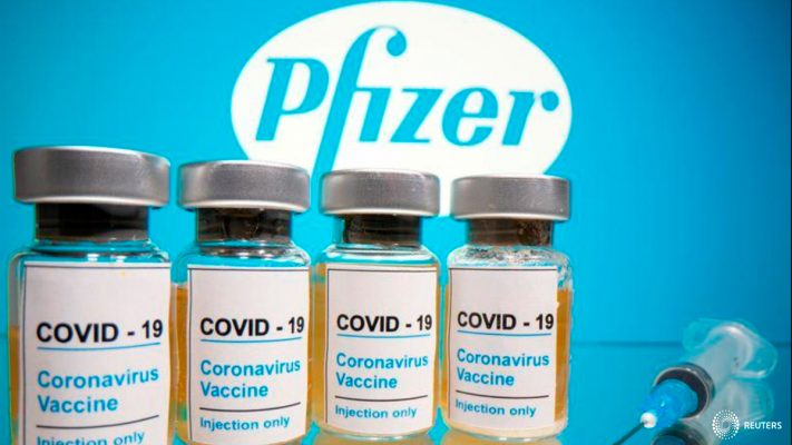 Vials with a sticker reading, "COVID-19 / Coronavirus vaccine / Injection only" and a medical syringe are seen in front of a displayed Pfizer logo in this illustration taken October 31, 2020. REUTERS/Dado Ruvic/Illustration