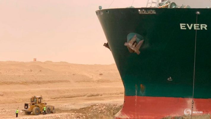 Los trabajadores son vistos junto a un buque portacontenedores que fue golpeado por el fuerte viento y encalló en el Canal de Suez, Egipto, el 24 de marzo de 2021. Autoridad del Canal de Suez/Folleto vía REUTERS