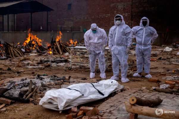 Hombres con trajes protectores están junto al cuerpo de su pariente, que murió de la enfermedad coronavirus (COVID-19), antes de su cremación en un campo crematorio en Nueva Delhi, India, el 4 de mayo de 2021. REUTERS/Siddiqui danés