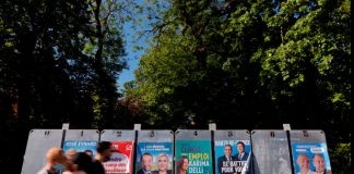 La extrema derecha francesa molesta por los resultados electorales, la región sur en juego Las personas, con una máscara facial protectora, pasan por delante de los paneles electorales antes de las próximas elecciones regionales francesas en Cambrai, Francia, 1 de junio de 2021. REUTERS/Pascal Rossignol