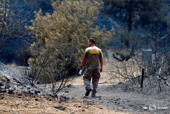 Un hombre camina junto a árboles quemados tras un incendio forestal cerca de la aldea de Ora, en la región montañosa de Larnaca, Chipre 4 de julio de 2021. REUTERS/George Christophorou
