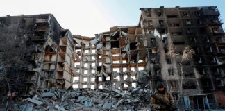 Las sirenas de los ataques aéreos suenan mientras Ucrania espera un alto el fuego de las conversaciones de paz Un miembro del servicio de las tropas prorrusas camina cerca de un edificio de apartamentos destruido en el curso del conflicto entre Ucrania y Rusia en la sitiada ciudad portuaria sureña de Mariupol, Ucrania, el 28 de marzo de 2022. REUTERS/Alexander Ermochenko