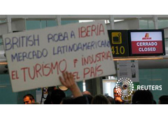 Un trabajador sostiene un cartel de protesta frente a un mostrador de facturación cerrado durante una huelga del personal de Iberia en la Terminal 1 de Barcelona, el 8 de marzo de 2013