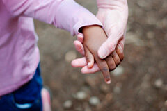 En una adopción ¿qué derechos tiene el adoptado, los adoptantes y la familia biológica? Un adulto cogiendo de la mano a una niña