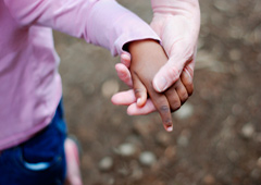Un adulto cogiendo de la mano a una niña