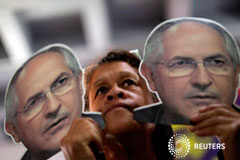 El opositor venezolano Antonio Ledezma vuelve a casa bajo arresto domiciliario una mujer sostiene retratos de Ledezma durante una conferencia de la coalición de partidos de oposición en Caracas, el 1 de agosto de 2017