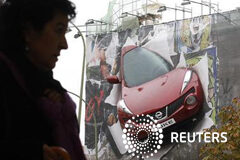 Las ventas de coches suben en enero un 2,5% interanual Una mujer pasa frente a un anuncio de un coche en Madrid el 2 de noviembre de 2011