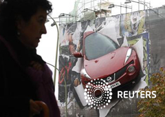 Una mujer pasa frente a un anuncio de un coche en Madrid el 2 de noviembre de 2011