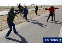 Un combatiente rebelde apunta a un supuesto simpatizante de Gadafi mientras otro rebelde le protege en una carretera entre Bengasi y Ajdabiya, cerca de Ajdabiya.