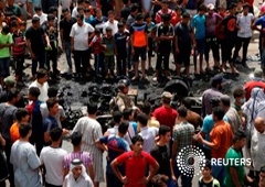 Un grupo de personas rodea los restos del coche bomba en Bagdad, el 11 de mayo de 2016