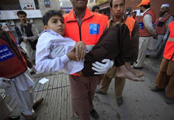 En la imagen del 13 de noviembre, un efectivo de los servicios de rescate se lleva a un chico herido en el atentado al hospital Lady Reading en Peshawar En la imagen del 13 de noviembre, un efectivo de los servicios de rescate se lleva a un chico herido en el atentado al hospital Lady Reading en Peshawar
