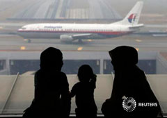 Dos mujeres y una niña frente a un avión de Malaysia Airlines en el aeropuerto de Kuala Lumpur el 13 de marzo de 2014