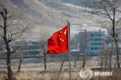 China insta a Corea del Norte a cumplir sus promesas de desnuclearización La bandera china en la parte china de la ribera del río Tumen, con un pueblo norcoreano al fondo, el 7 de enero de 2016