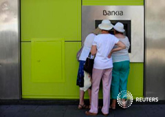 Gente usa un cajero de Bankia en Sevilla, el 24 de junio de 2013
