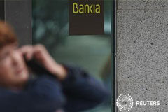 Bankia contempla una amplia reducción de plantilla y espera beneficios en 2013 Una mujer habla pr teléfono frente a una sucursal de Bankia en Madrid, el 26 de octubre de 2012.