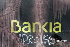 El Gobierno ultima un plan de saneamiento de Bankia Una mujer pasa por delante de un poster con pintada incluida de la entidad financiera Bankia, en Madrid