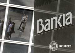 Los peatones se reflejan en el edificio de la sede Bankia en Madrid