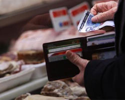 Un hombre saca un billete de 20 euros para pagar en una carnicería.
