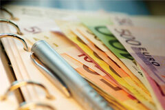 Prevenir e impedir el blanqueo de capitales Distintos billetes de euro y un bolígrafo sobre una libreta