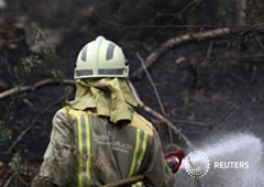 Un bombero refrescando el terreno en el parque situado en el consejo de A Capela, en la provincia de Coruña
