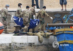 Unos soldados llevan el cadáver de una víctima del naufragio en Lampedusa, el 6 de octubre de 2013