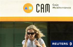 Una mujer camina frente a una sucursal de la Caja de Ahorros del Mediterráneo (CAM) en Madrid, el 24 de mayo de 2010.