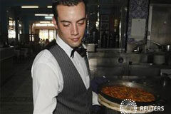 El PMI del sector servicios ralentiza su contracción en diciembre En la imagen de archivo, un camarero muestra una paella en un restaurante de la playa de la Malvarrosa en Valencia, el 20 de julio de 2012