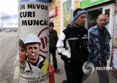 En la imagen, varias personas pasan junto a un cartel que demanda más trabajo en Zlatna, a 420 km al noroeste de Bucarest el 8 de diciembre de 2012