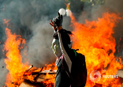 Un manifestante enmascarado gesticula frente a una barricada en llamas durante una protesta en Providencia, un barrio acomodado, en Santiago. 6 de noviembre de 2019.
