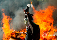 Un manifestante enmascarado gesticula frente a una barricada en llamas durante una protesta en Providencia, un barrio acomodado, en Santiago. 6 de noviembre de 2019. Un manifestante enmascarado gesticula frente a una barricada en llamas durante una protesta en Providencia, un barrio acomodado, en Santiago. 6 de noviembre de 2019.