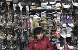 El crecimiento económico de China se acelera una vendedora espera por clientes en su puesto de zpaatos en un mercado en Shenyang, en la provincia de Liaoning, el 21 de enero de 2010.