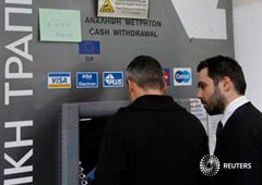 Unos hombres retirando dinero de un cajero del Laiki Bank en Nicosia el 22 de marzo con un cartel que les informa que solo pueden retirar 260 euros