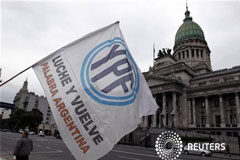 El Senado de Argentina aprueba la expropiación de YPF Un hombre ondea una bandera con el logo de YPF frente al Congreso argentino