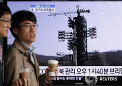 hombres surcoreanos pasan una pantalla mostrando un reportaje de noticias sobre el lanzamiento de un cohete en Corea del Norte, en Seúl