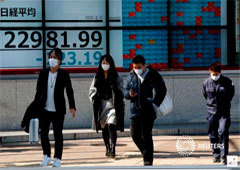 Personas con mascarillas pasan por delante de una pantalla que muestra el índice Nikkei en Tokio, Japón 3 de febrero de 2020.