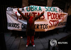 Una activista celebra la ocupación de un edificio vacío frente a una pancarta antidesahucios, en el centro de Madrid el 5 de enero de 2014