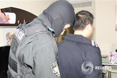 Unos 80 detenidos en una redada contra el blanqueo de dinero Difundida por la Policái Nacional, un agente detiene a un ciudadano chino en la operación desarrollada en varias provincias